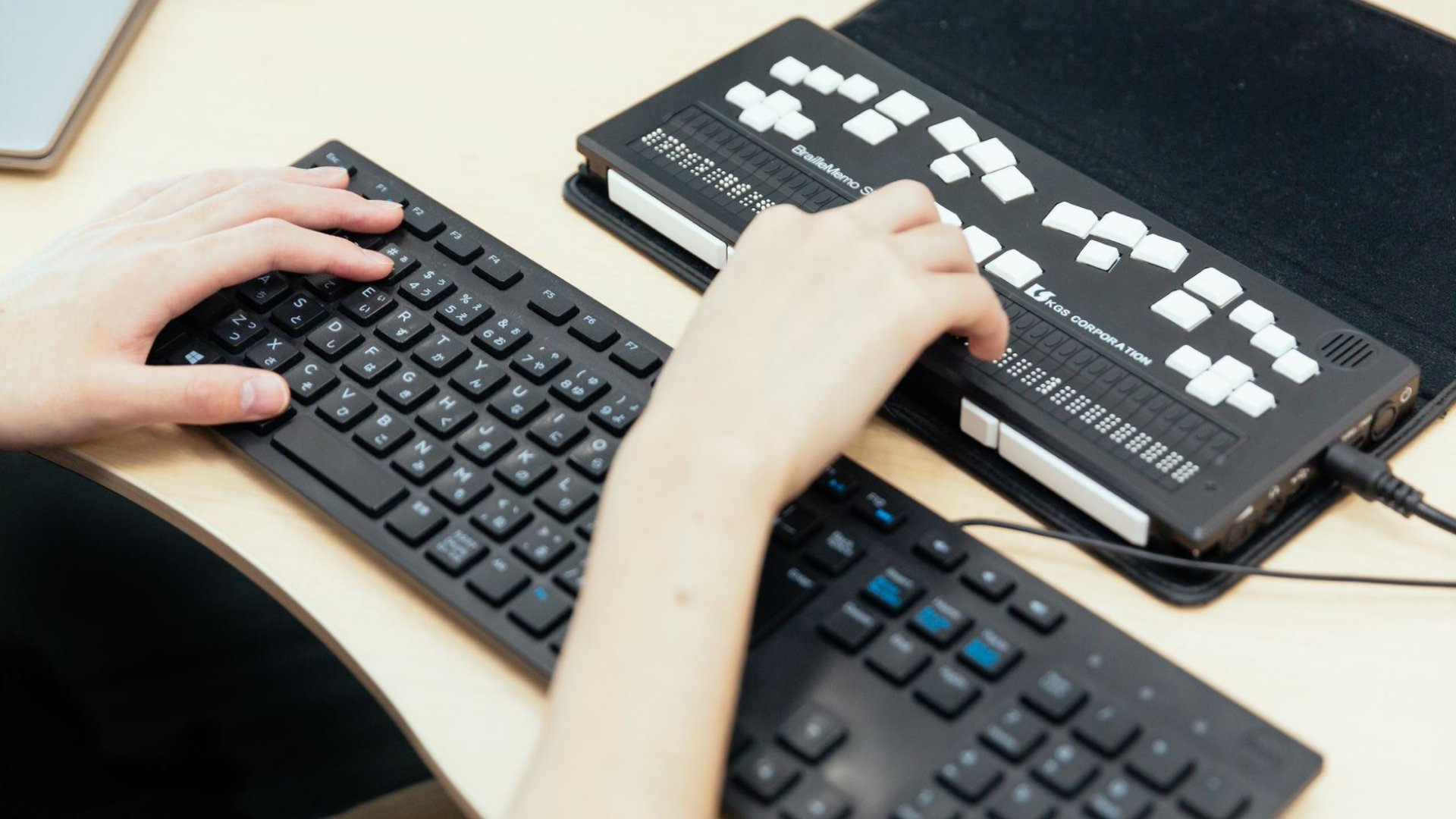 パソコンのキーボードと、点字読み上げ用のキーボードを利用している手元の様子